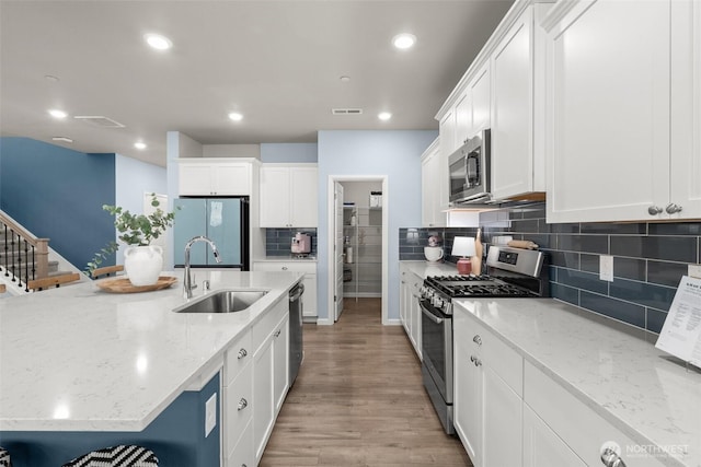 12011 SE 299th Pl, Auburn, WA 98092 - kitchen with backsplash, a sink, light wood-style floors, stainless steel appliances, and white cabinetry