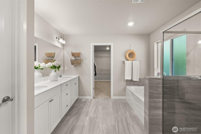 12011 SE 299th Pl, Auburn, WA 98092 - bathroom featuring double vanity, baseboards, a bath, a spacious closet, and a sink
