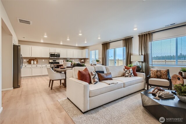 living room featuring recessed lighting, visible vents, and light wood-type flooring
