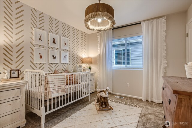 bedroom with carpet floors, baseboards, a crib, and visible vents