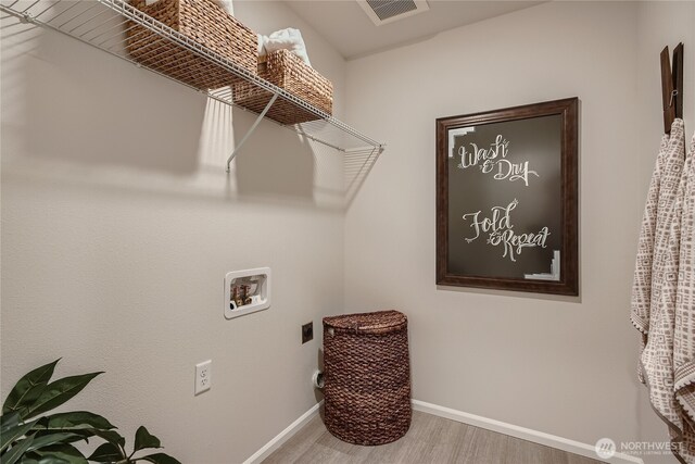 clothes washing area with laundry area, visible vents, wood finished floors, baseboards, and hookup for a washing machine