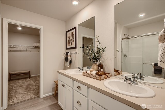 bathroom featuring a sink, wood finished floors, and a stall shower
