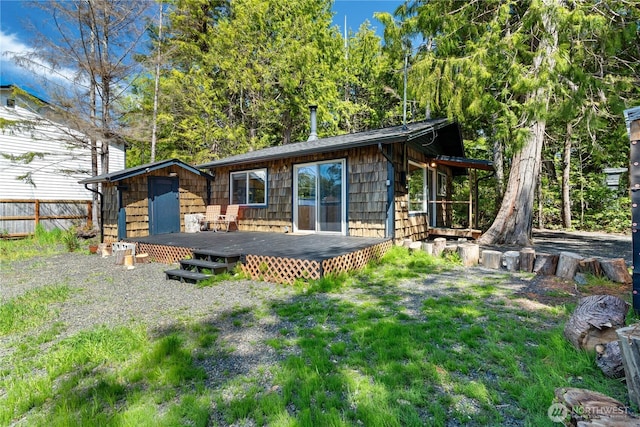 back of property with a yard, a deck, and fence