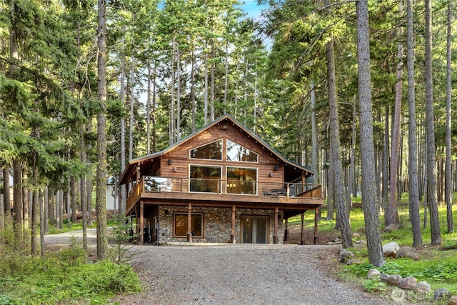 1570 Skull Springs Rd, Cle Elum, WA 98922 - view of front facade featuring stone siding, gravel driveway, a deck, and a forest view