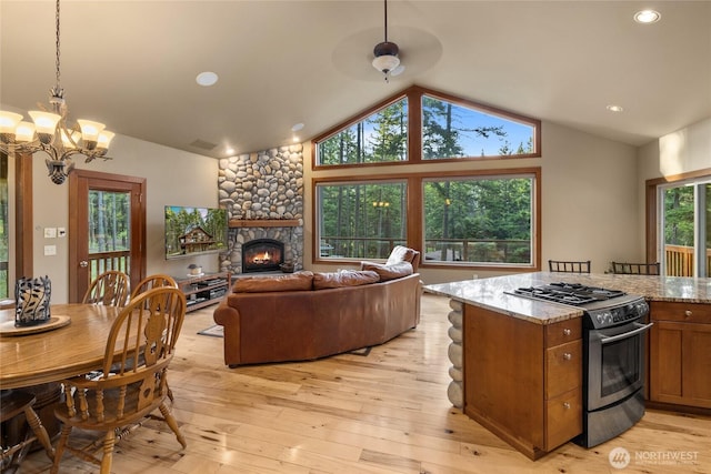 1570 Skull Springs Rd, Cle Elum, WA 98922 - kitchen featuring stainless steel range with gas cooktop, brown cabinets, lofted ceiling, a stone fireplace, and light wood-style floors
