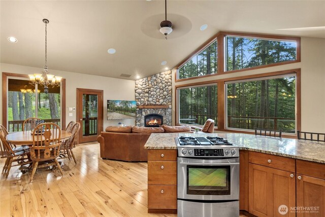 1570 Skull Springs Rd, Cle Elum, WA 98922 - kitchen featuring gas range, a chandelier, light wood-style flooring, a stone fireplace, and brown cabinets
