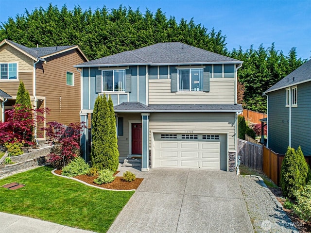 traditional home featuring fence, a shingled roof, an attached garage, a front yard, and driveway
