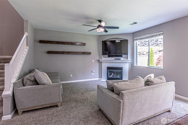 living room featuring baseboards, a fireplace, a ceiling fan, and visible vents