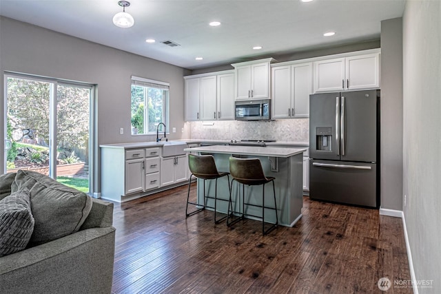 kitchen featuring appliances with stainless steel finishes, a breakfast bar, light countertops, white cabinetry, and visible vents