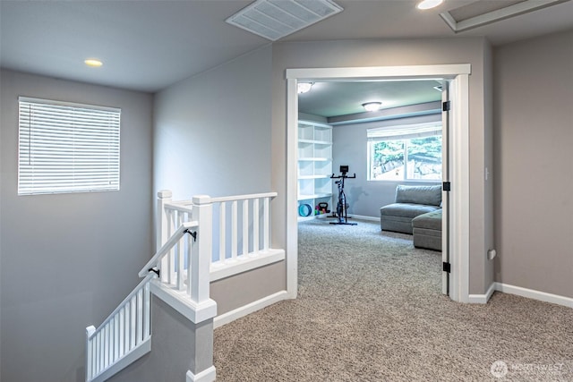 hallway with baseboards, visible vents, carpet, and an upstairs landing