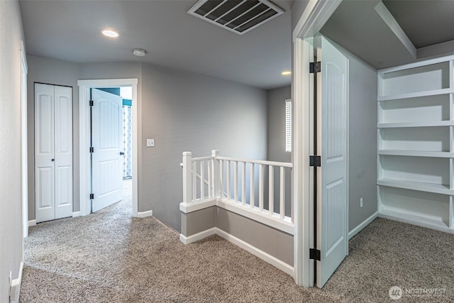 hall with visible vents, baseboards, an upstairs landing, carpet, and recessed lighting