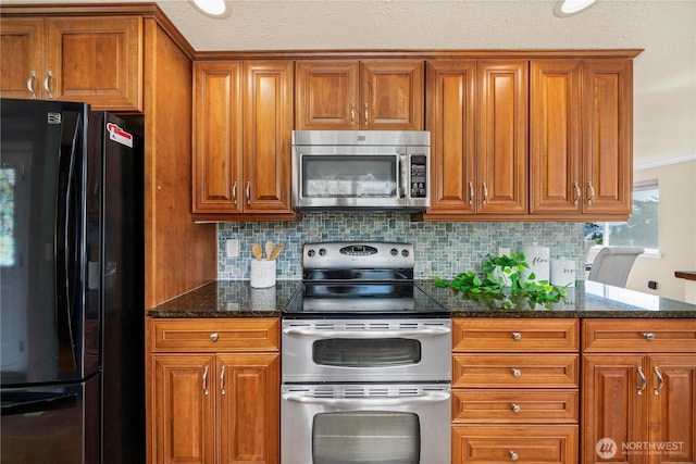 1319 Madrona Way NW, Gig Harbor, WA 98332 - kitchen featuring brown cabinets, tasteful backsplash, dark stone counters, and appliances with stainless steel finishes
