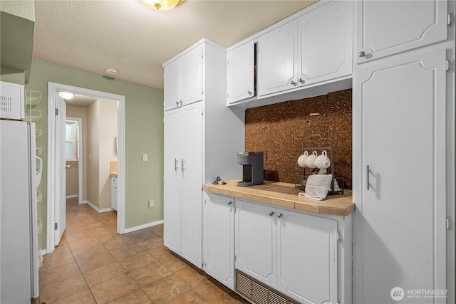 1319 Madrona Way NW, Gig Harbor, WA 98332 - kitchen with freestanding refrigerator, light countertops, baseboards, and white cabinets