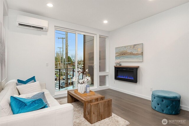 living room featuring a wall unit AC, wood finished floors, healthy amount of natural light, recessed lighting, and baseboards