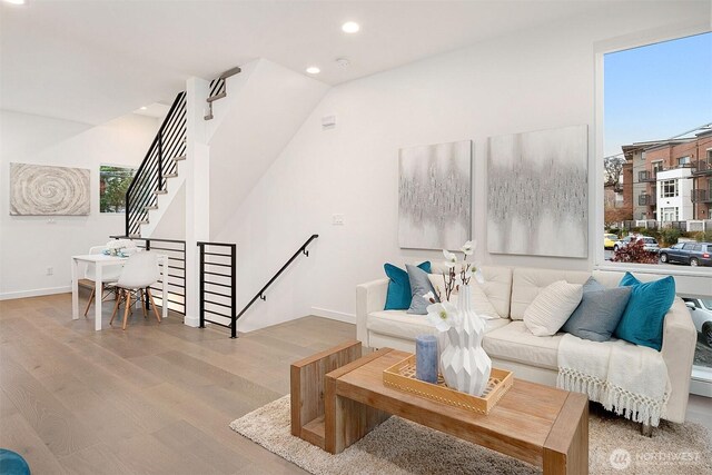 living area featuring wood finished floors, recessed lighting, baseboards, and stairs
