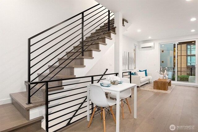 stairs featuring a wall mounted AC, wood finished floors, recessed lighting, and baseboards