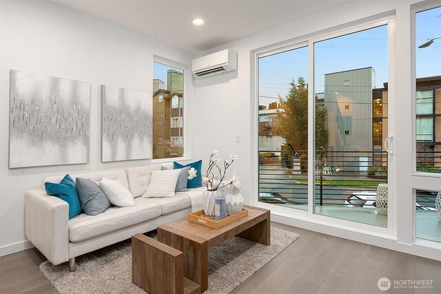 living room with a wall mounted air conditioner, wood finished floors, recessed lighting, and baseboards