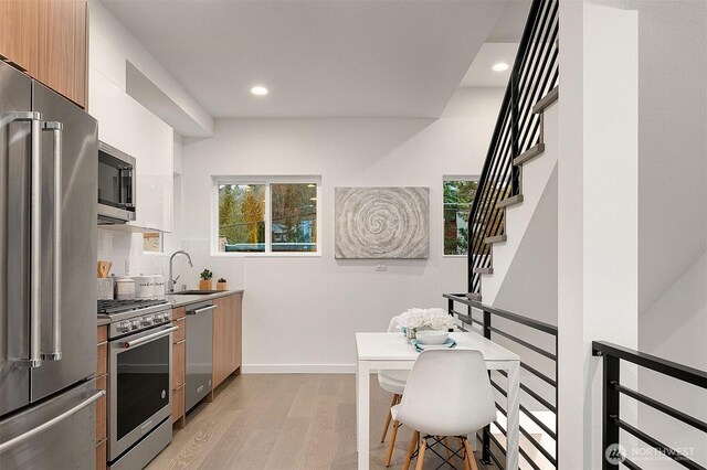 kitchen with stainless steel appliances, modern cabinets, light wood-type flooring, plenty of natural light, and recessed lighting