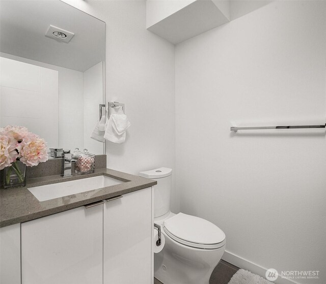 bathroom with toilet, vanity, baseboards, and tile patterned floors