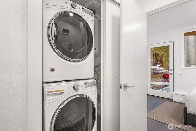 laundry room with stacked washer / dryer and wood finished floors