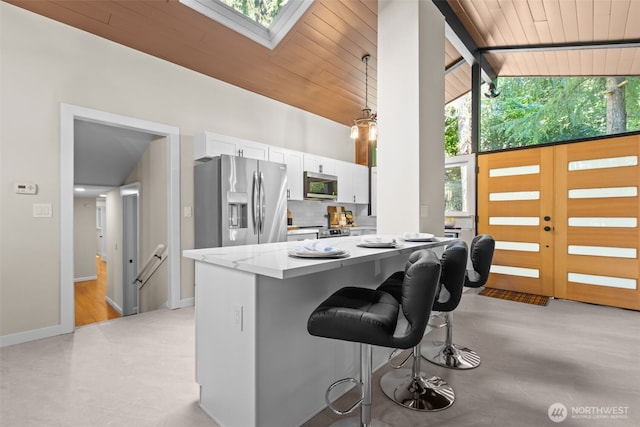 18265 47th Pl NE, Lake Forest Park, WA 98155 - kitchen with stainless steel appliances, white cabinets, a kitchen bar, a skylight, and a wooden ceiling with exposed beams