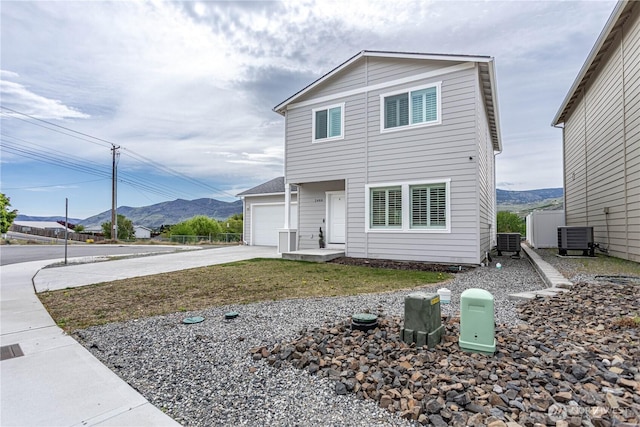 view of front of property with central air condition unit, concrete driveway, a mountain view, and a garage