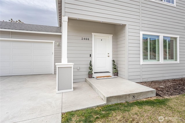 view of exterior entry with concrete driveway and an attached garage