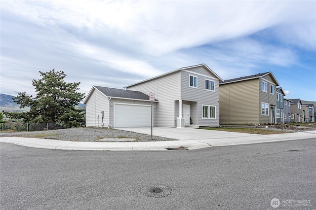 traditional-style home with an attached garage, fence, a residential view, and concrete driveway