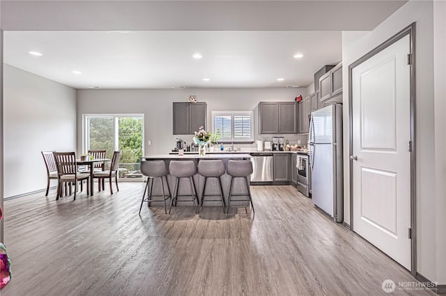 kitchen featuring light wood-style floors, a kitchen breakfast bar, a center island, light countertops, and appliances with stainless steel finishes
