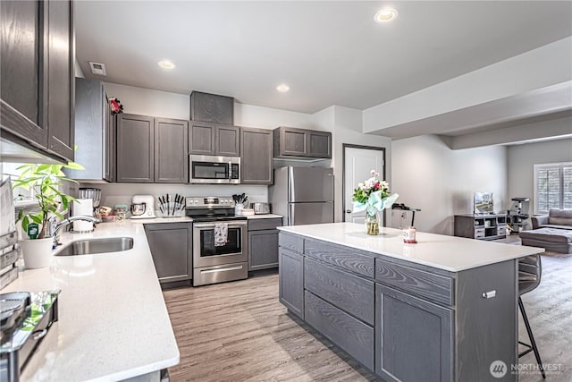 kitchen featuring a sink, light countertops, stainless steel appliances, and a kitchen bar