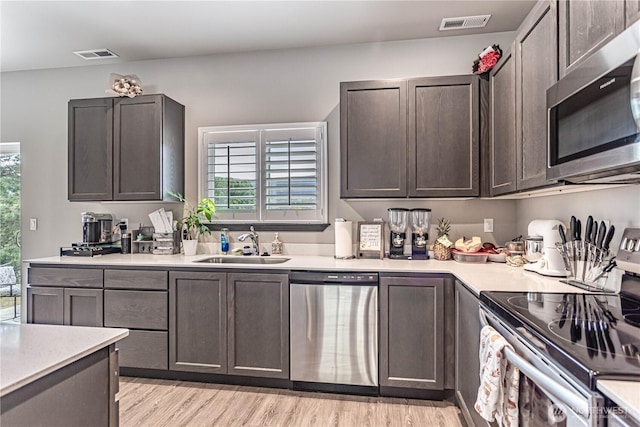 kitchen with light countertops, appliances with stainless steel finishes, a sink, and visible vents