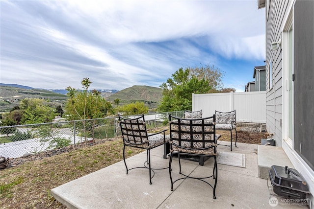 view of patio / terrace featuring fence, outdoor dining area, and a mountain view