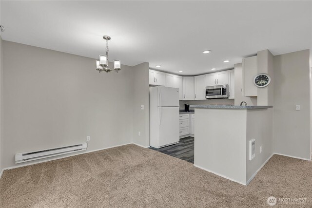 kitchen featuring white cabinets, stainless steel microwave, a baseboard heating unit, dark colored carpet, and freestanding refrigerator