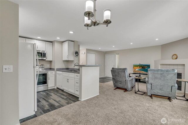 kitchen featuring a sink, dark colored carpet, open floor plan, stainless steel appliances, and white cabinetry