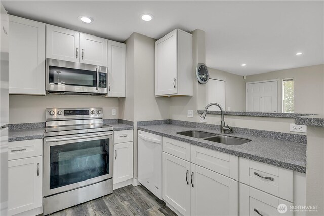 kitchen with dark wood-style flooring, appliances with stainless steel finishes, a sink, white cabinets, and recessed lighting