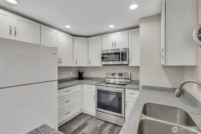 kitchen with a sink, light countertops, stainless steel appliances, recessed lighting, and white cabinetry