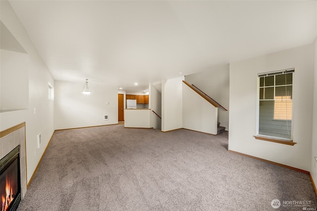 unfurnished living room with stairs, baseboards, light colored carpet, recessed lighting, and a tiled fireplace