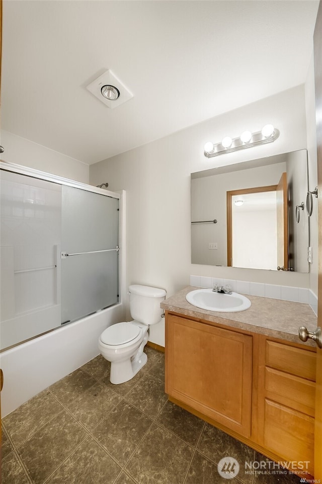 bathroom with vanity, tile patterned flooring, bath / shower combo with glass door, and toilet