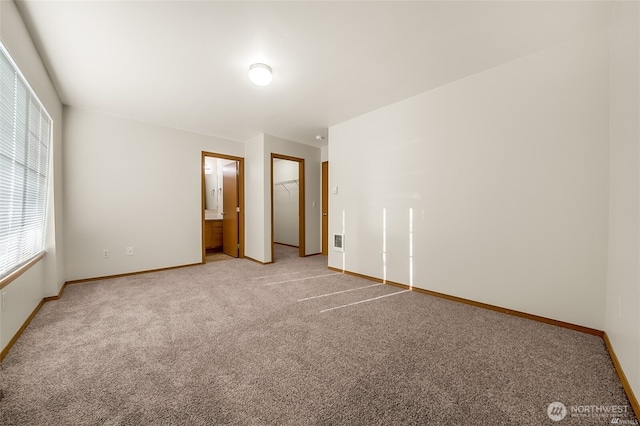 unfurnished bedroom featuring baseboards, light carpet, a closet, and a walk in closet