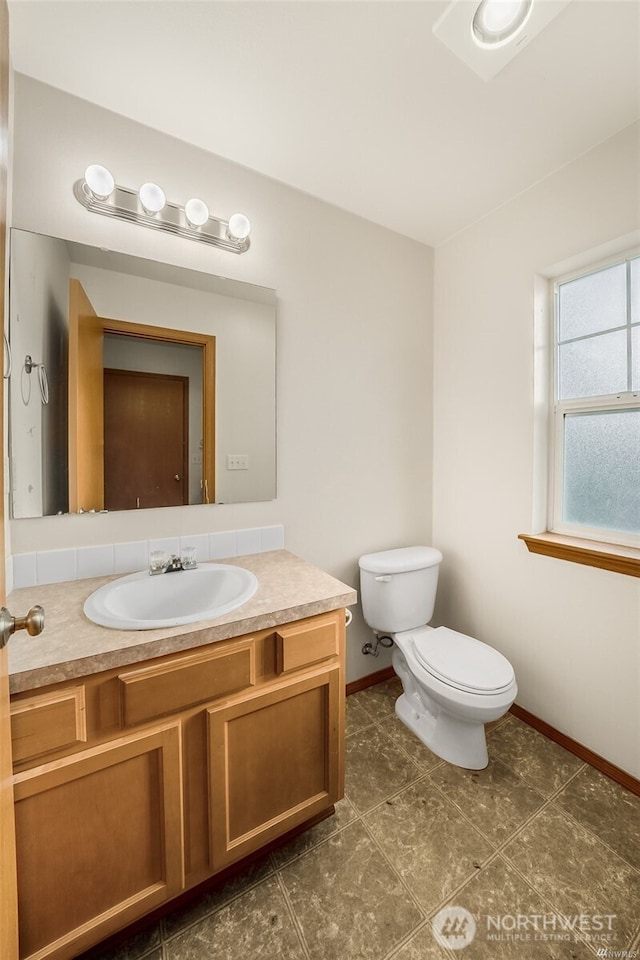 bathroom with baseboards, vanity, and toilet