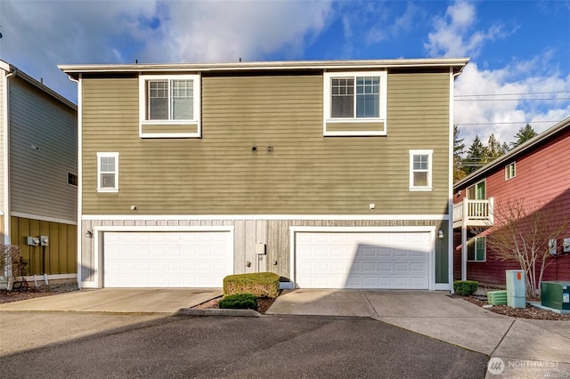 view of front of house featuring an attached garage, central AC unit, and concrete driveway