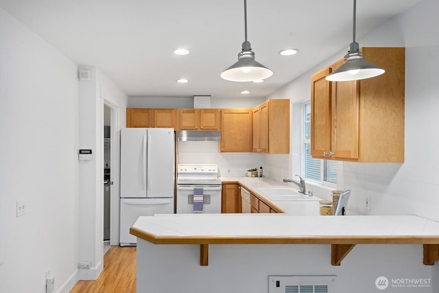 kitchen with white appliances, recessed lighting, under cabinet range hood, tasteful backsplash, and a sink