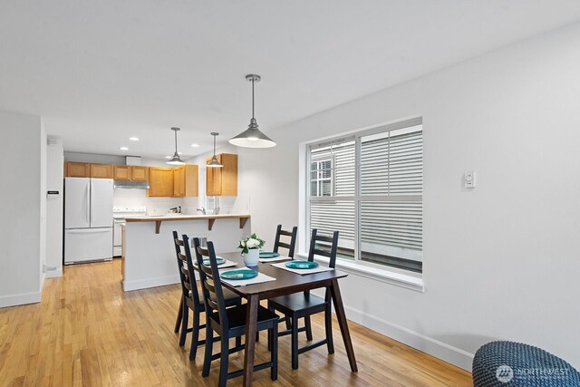 dining space featuring baseboards, recessed lighting, and light wood finished floors