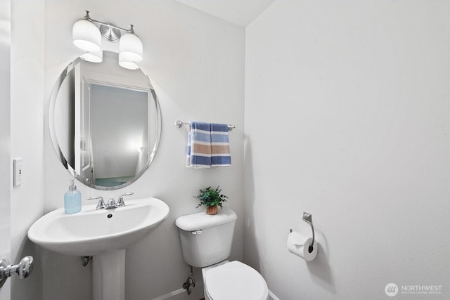 half bath featuring baseboards and toilet