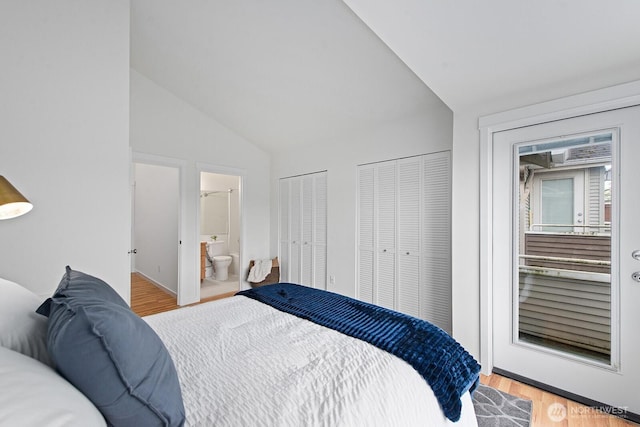 bedroom with two closets, vaulted ceiling, wood finished floors, and connected bathroom