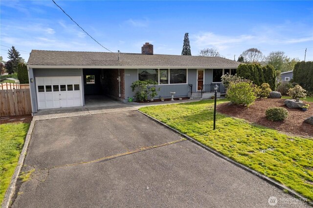 single story home with fence, a front lawn, an attached carport, a chimney, and driveway