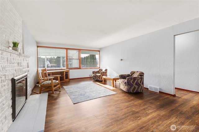 living area with visible vents, wood finished floors, and a fireplace