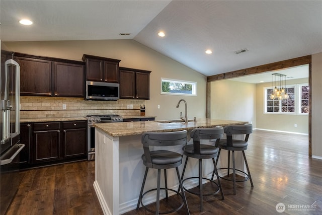301 NE Danner Ln, College Place, WA 99324 - kitchen with appliances with stainless steel finishes, vaulted ceiling, dark brown cabinets, a sink, and light stone counters
