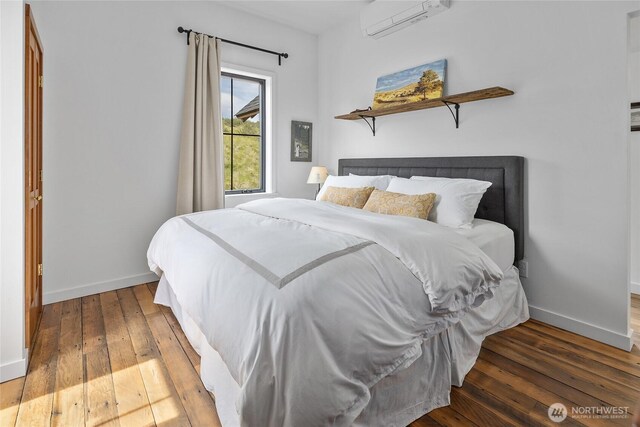 bedroom with baseboards, a wall mounted air conditioner, and hardwood / wood-style floors