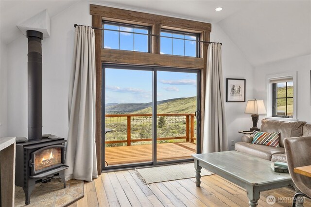 doorway to outside featuring a wood stove, light wood-style floors, high vaulted ceiling, recessed lighting, and a mountain view